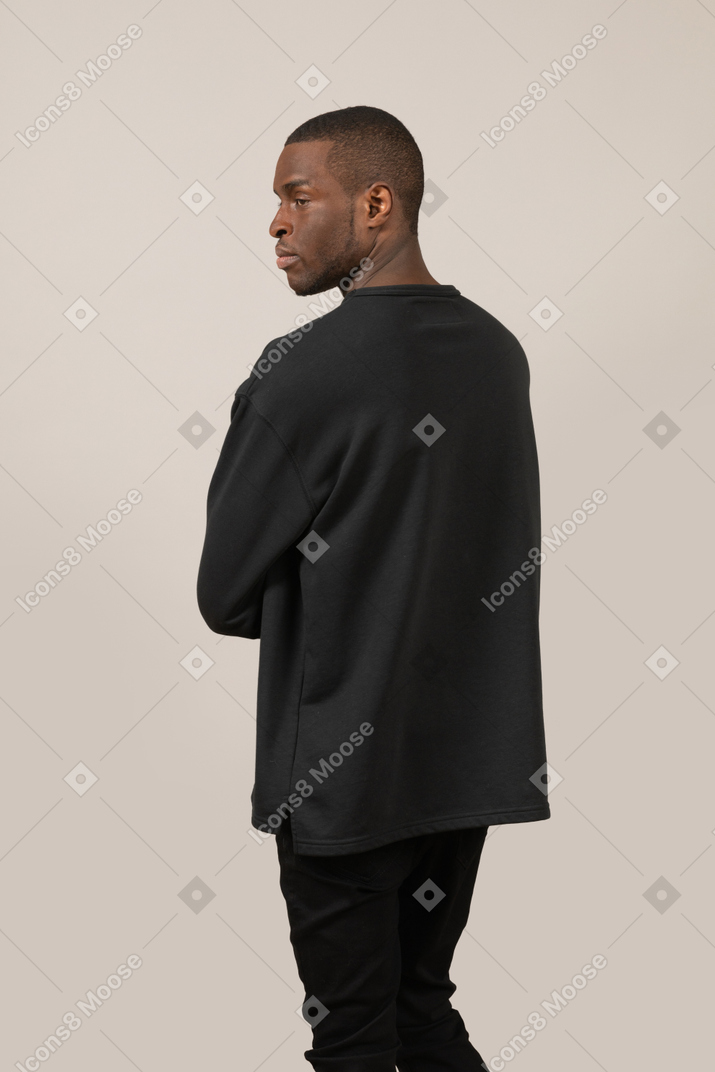 Three-quarter back view of young man looking aside