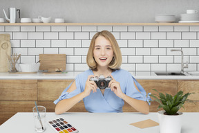 A woman sitting at a table holding a camera