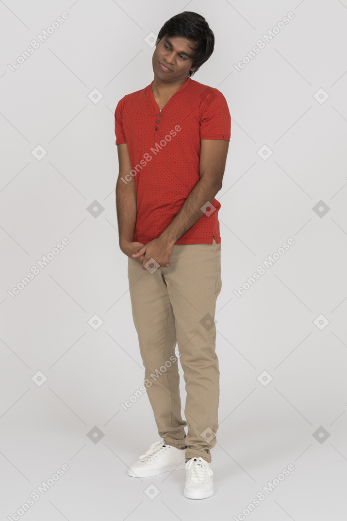 Hesitating young man standing with folded hands