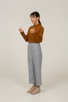 Three-quarter view of a young asian female in breeches and blouse showing thumbs up