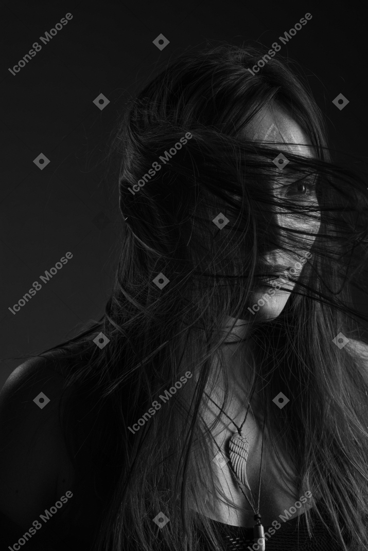 Noir three-quarter portrait of a young female with ethnic facial art and messy hair