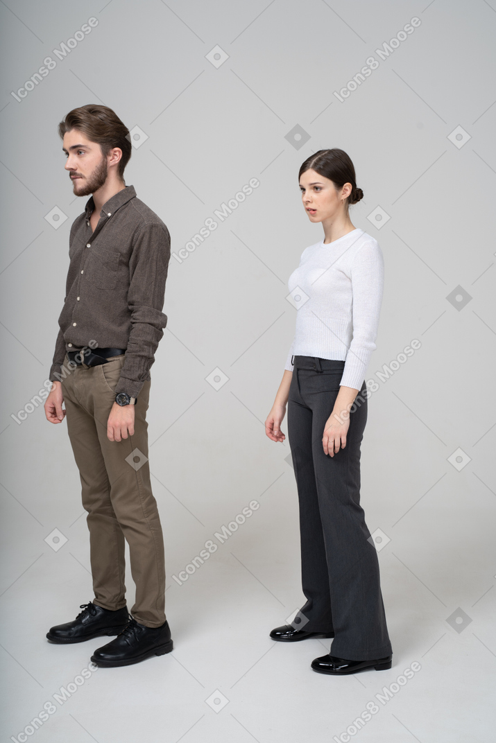 Трехчетвертный вид молодой пары в офисной одежде, кусающей губы