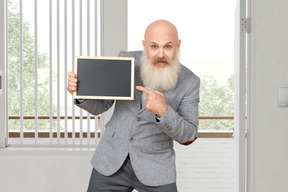 A bald man with a beard holding a blackboard
