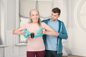 Man helping an elderly woman to exercise