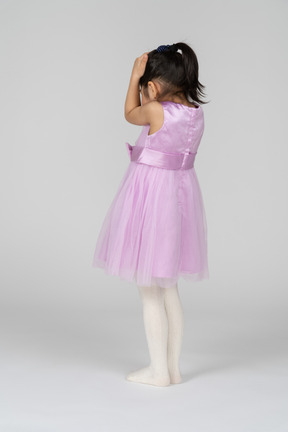 Back view of a little girl in a tutu dress covering her head