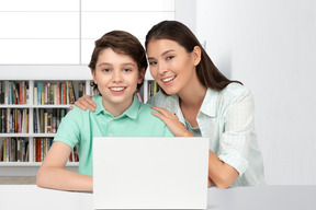 Mom and son sitting at a table with a laptop