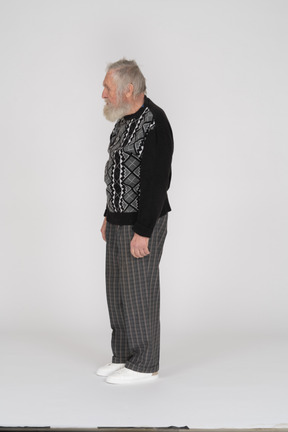 Side view of elderly man in dark clothes standing