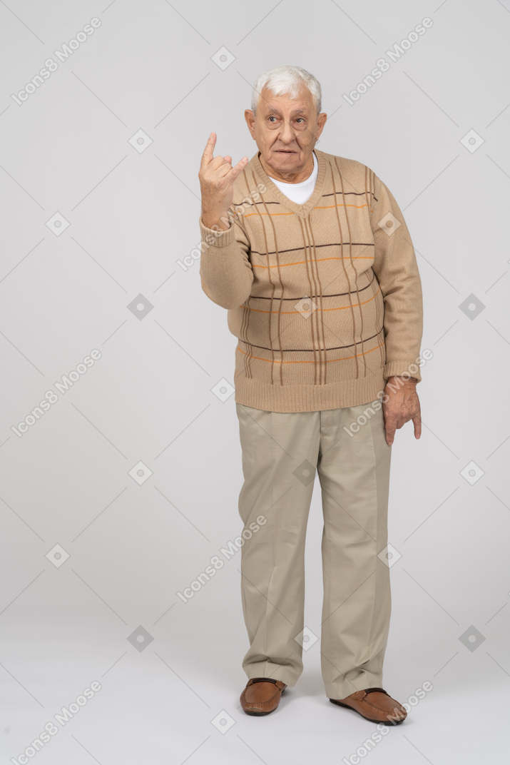 Vista frontal de um velho em roupas casuais, mostrando o gesto de rock