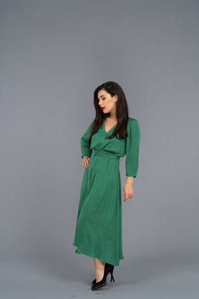 腰に手を置いて緑のドレスを着た魅力的な若い女性の4分の3のビュー