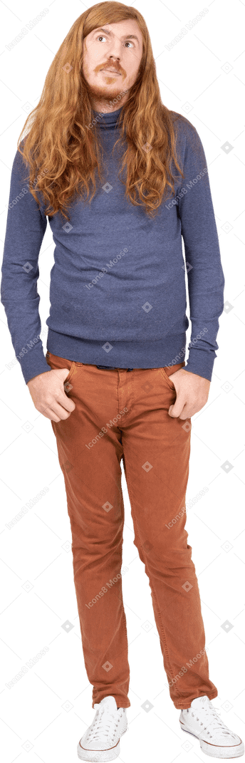 Vista frontal de un joven pensativo de pie con las manos en los bolsillos