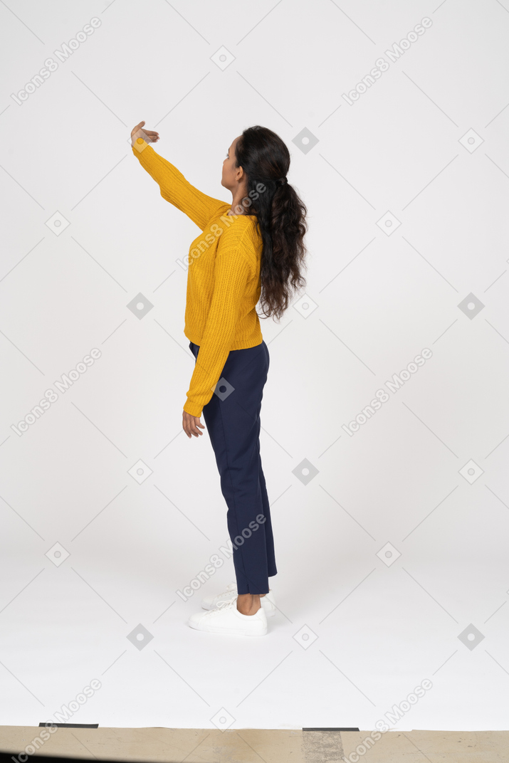Side view of a girl in casual clothes standing with raised arm