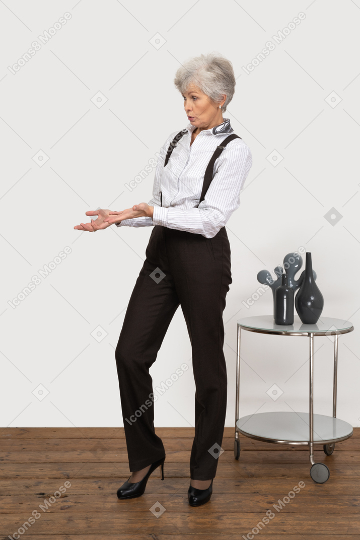 Front view of an old lady in office clothing pointing aside