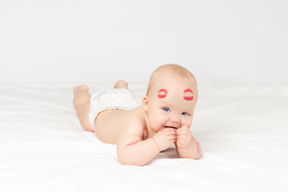 Smiling baby girl with red lipstick kisses