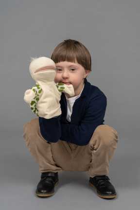 Portrait of a little boy on haunches holding a tortoise puppet