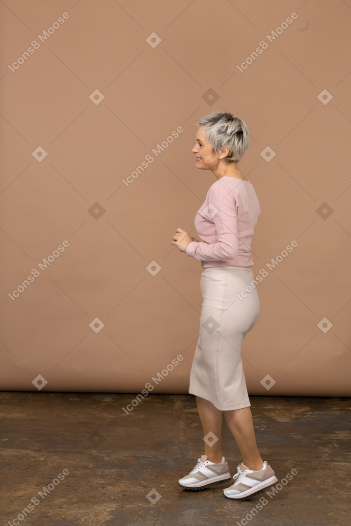 Vista laterale di una donna felice in abiti casual che cammina