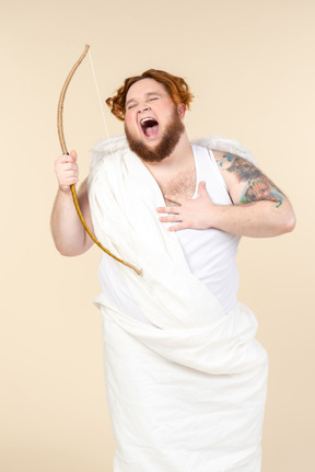 Laughing big guy dressed as a cupid holding bow