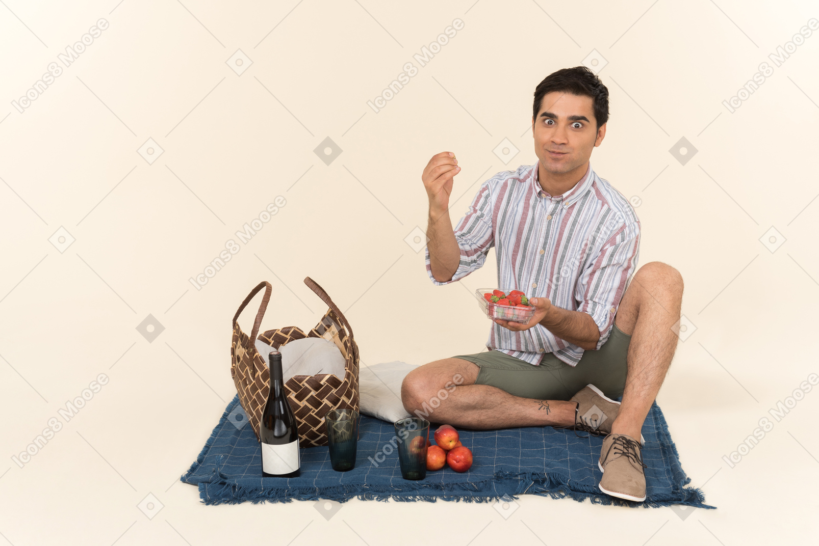 Возбужденный молодой кавказский человек ест фрукты во время пикника