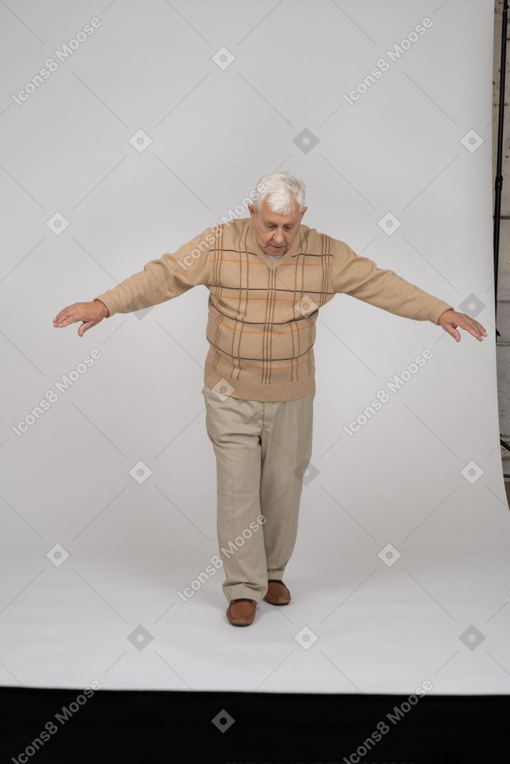 腕を伸ばして前に歩くカジュアルな服装の老人の正面図