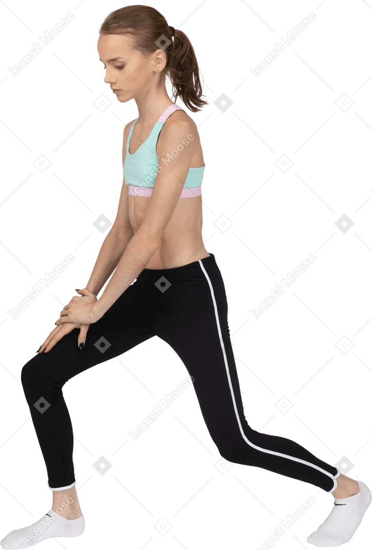 Vista lateral de una jovencita en ropa deportiva haciendo una estocada