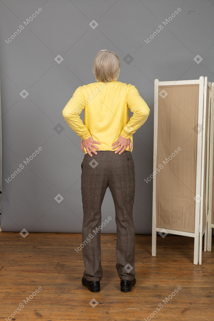 Back view of an old man with a pain in his back