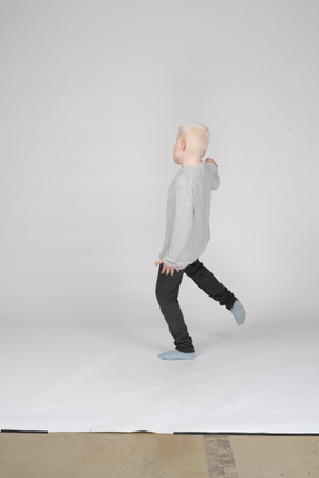 Back view of boy kicking his leg in the air