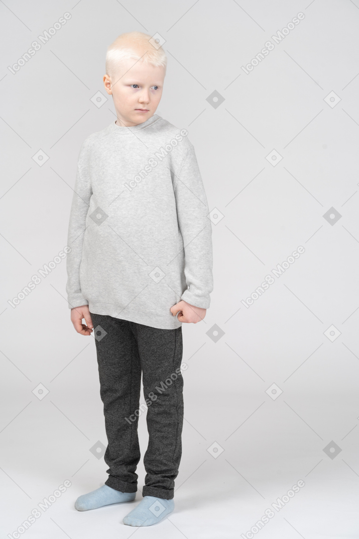 Vista frontal de um garotinho loiro olhando de lado