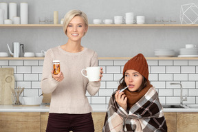 Smiling woman holding cup of tea and pills for a sick friend