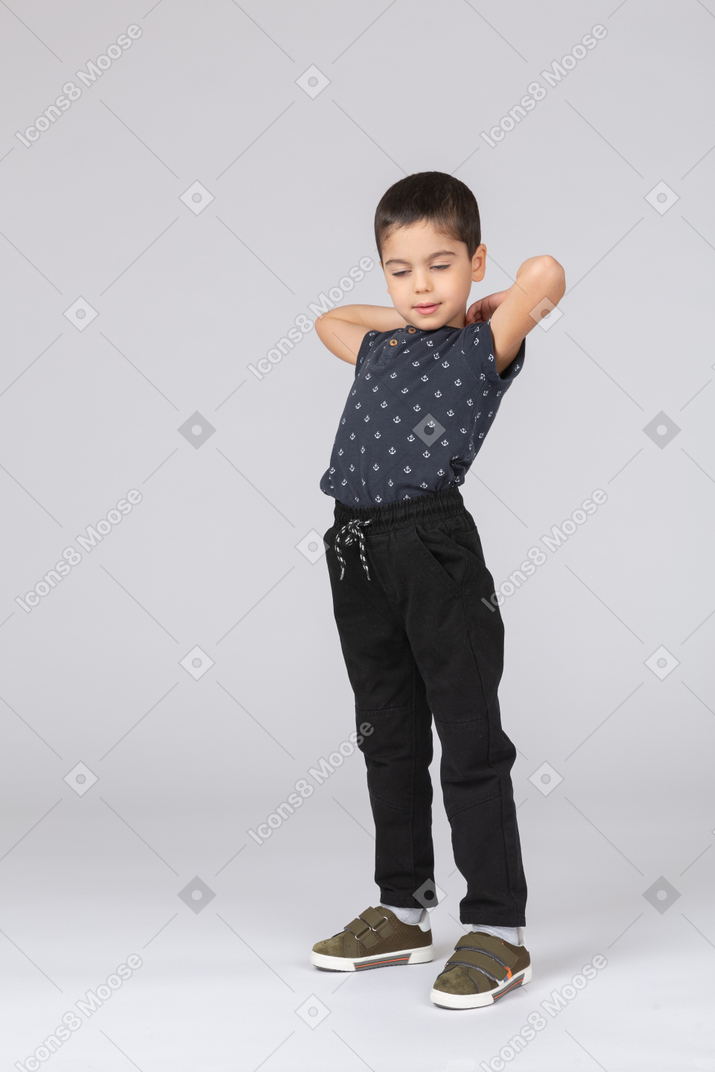 Front view of a cute boy in casual clothes stretching with hands behind head