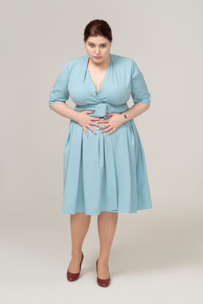 一位身着蓝色连衣裙、胃痛的女人的前视图
