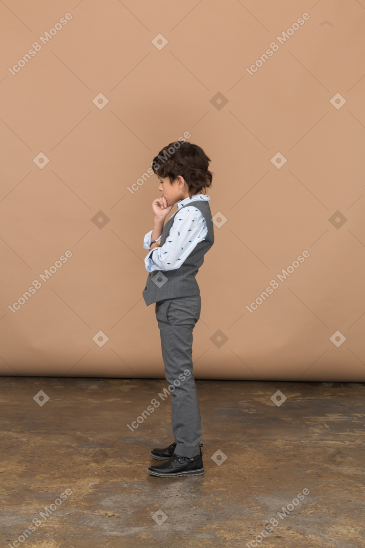 Side view of a thoughtful cute boy in suit