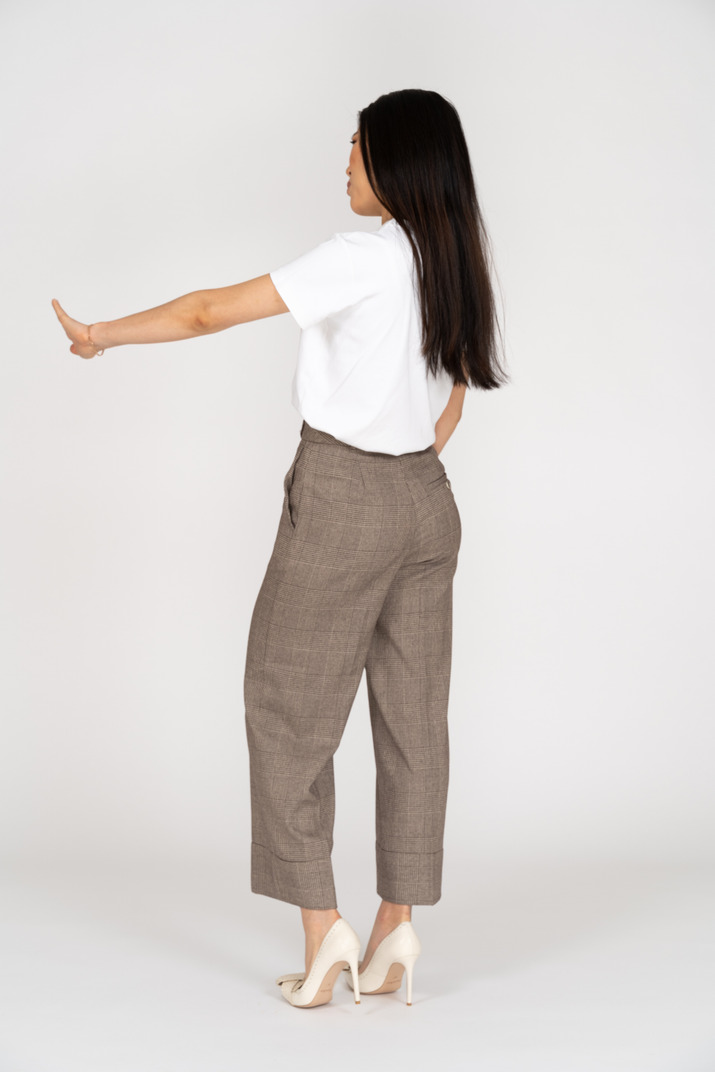 Three-quarter back view of a young woman in breeches outstretching her hand