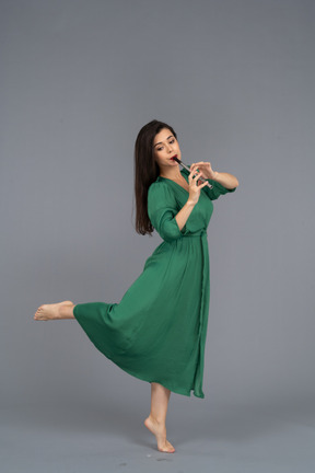 フルートを演奏する緑のドレスを着た裸足の若い女性の側面図