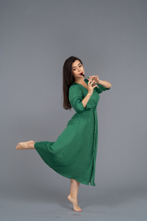 Side view of a barefooted young lady in green dress playing the flute