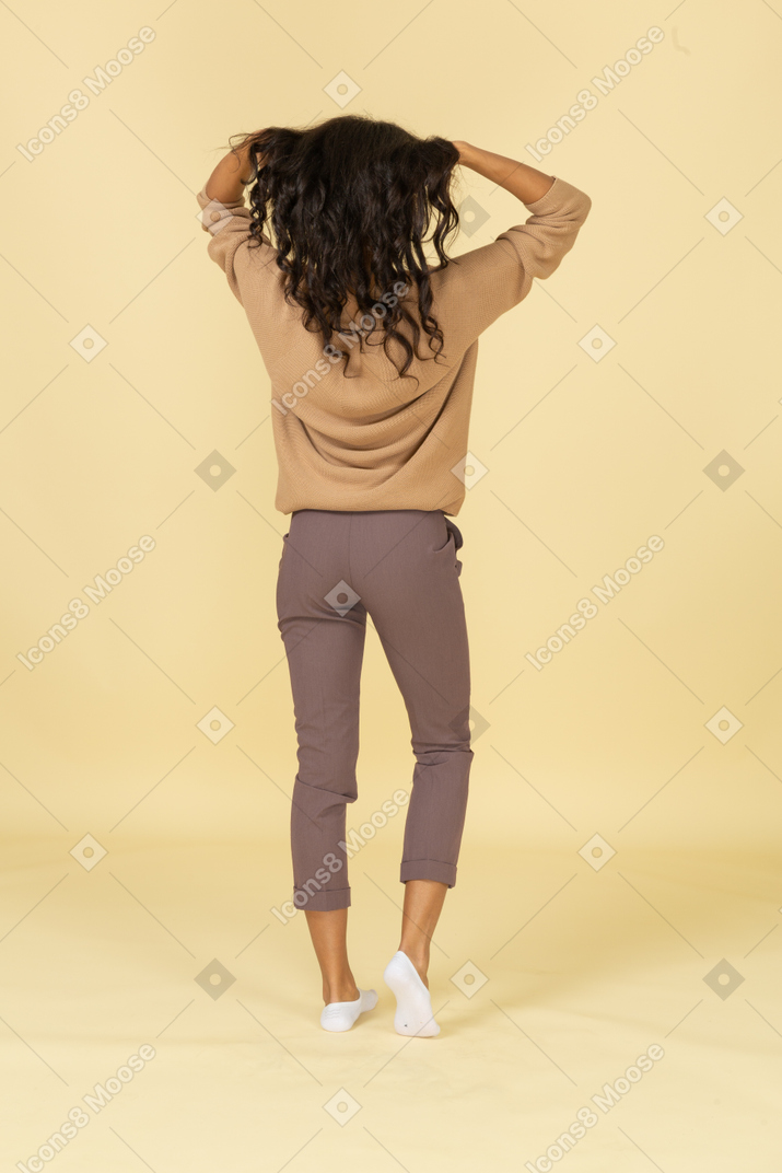 Vista posteriore di una giovane donna dalla carnagione scura che fissa i suoi capelli