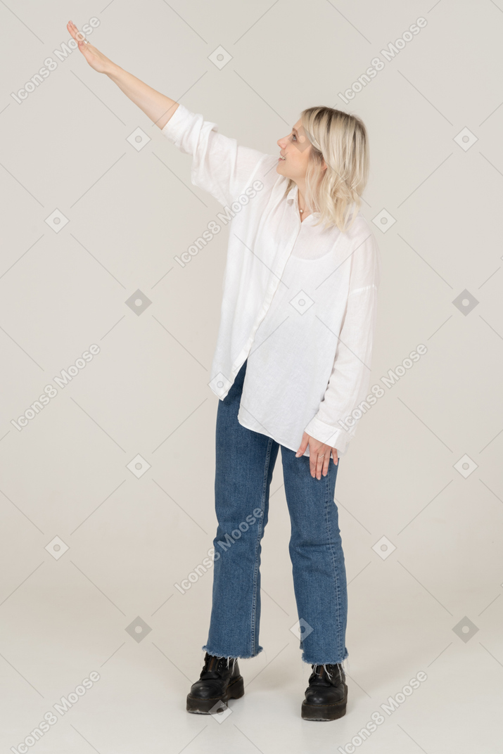 一个年轻的金发女性，转过身去，举起手的前视图