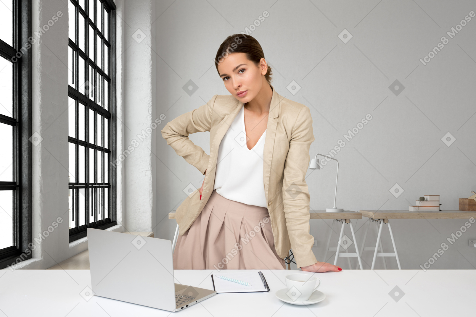 A business woman standing at a desk with a laptop
