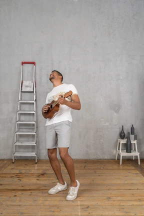 Dreiviertelansicht eines mannes, der ukulele spielt und sich glücklich zurücklehnt