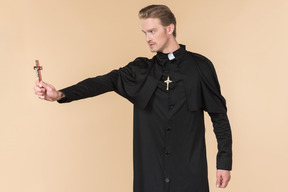 Catholic priest standing in profile and holding cross