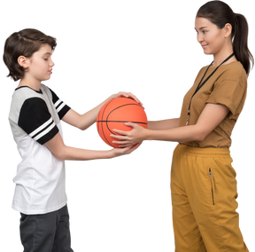 Pe female teacher and pupil holding a basketball ball
