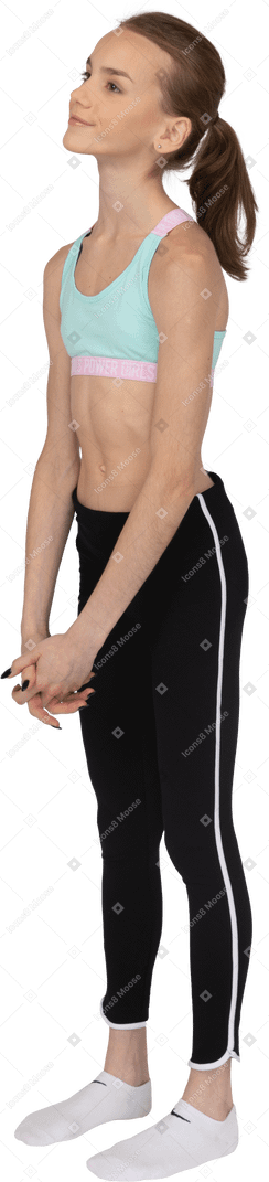 Vista lateral de una jovencita en ropa deportiva cogidos de la mano y mirando a un lado
