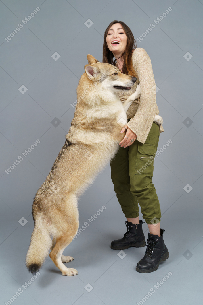 Figura intera di un maestro femmina felice che gioca con il suo cane