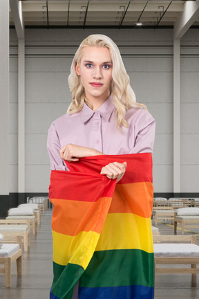 A woman holding a rainbow flag in a room