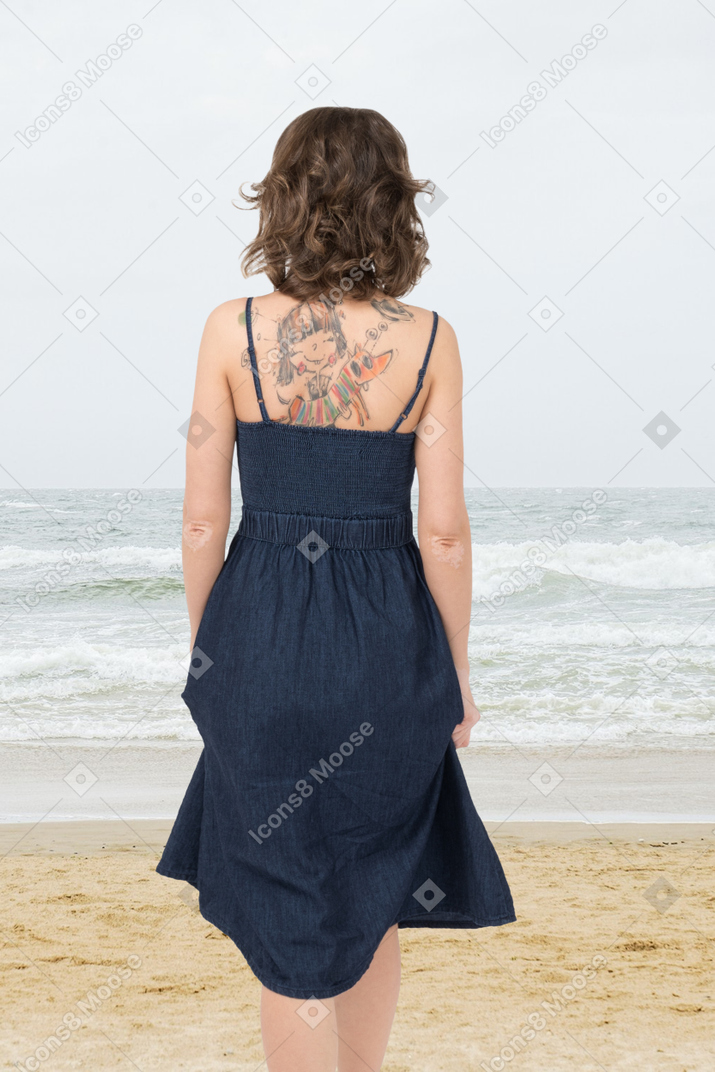 A woman standing on a beach looking at the ocean