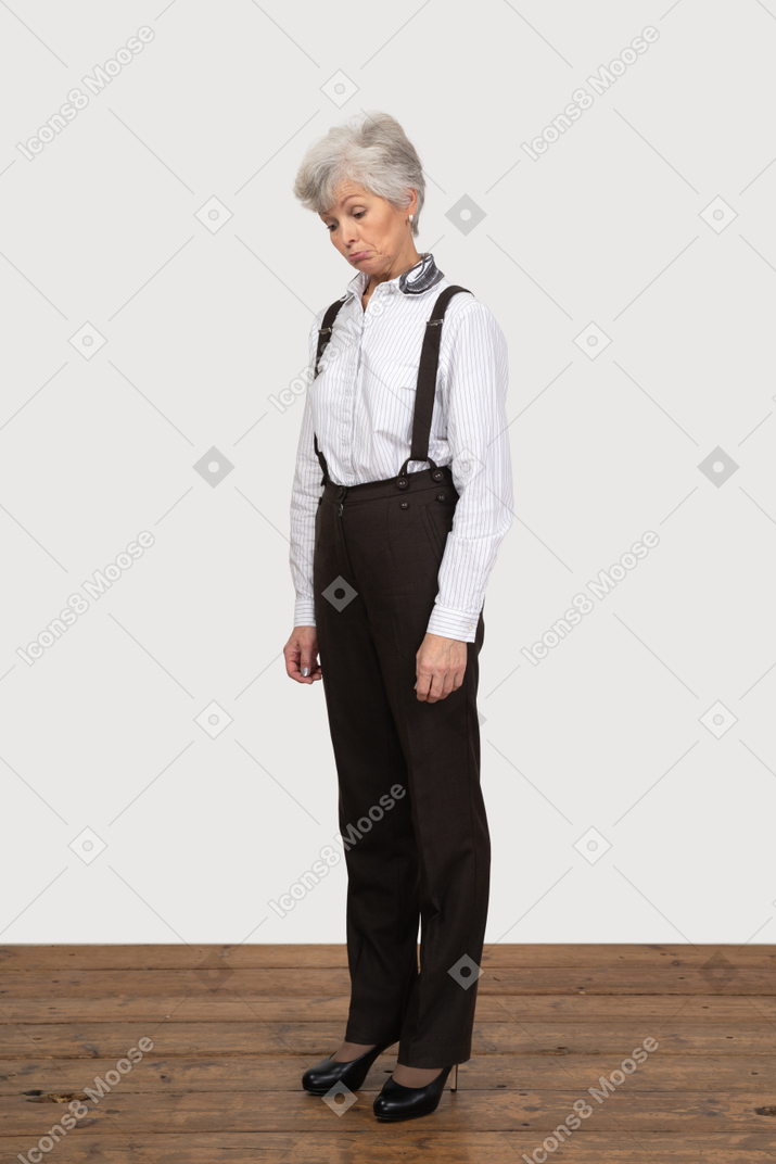 Three-quarter view of a perplexed old lady in office clothing looking down surprisingly