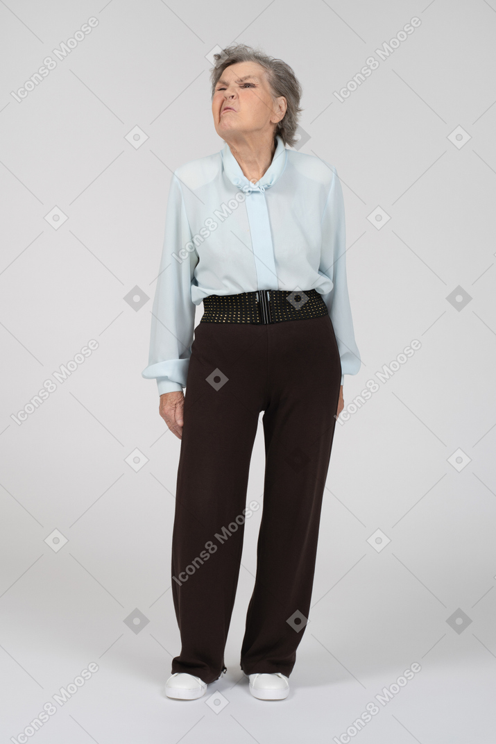 Vue de face d'une vieille femme en vêtements formels grimaçant vers la gauche
