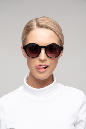 Mulher atraente usando óculos escuros e mostrando a língua