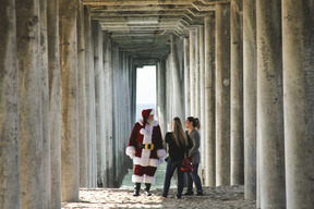 Zwei frauen sprechen mit dem weihnachtsmann am strand
