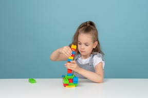 Bambina che costruisce una torre da blocchi di costruzione