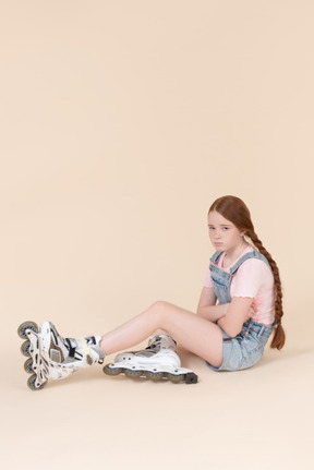 Sad looking teenage girl wearing rollerblades sitting on the floor