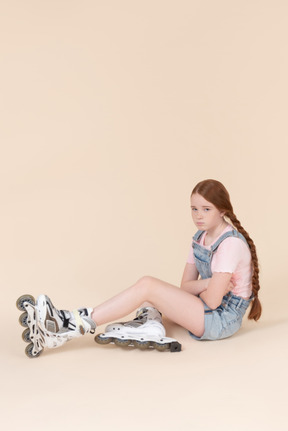 바닥에 앉아 rollerblades를 입고 슬픈 찾고 십 대 소녀